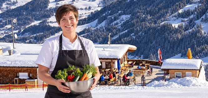 freundliche-kuechenhilfe-vor-verschneiter-berghuette