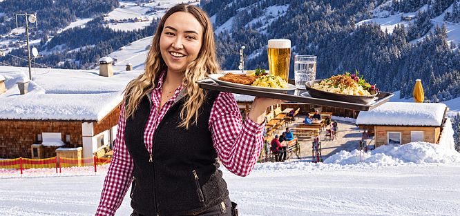 kellnerin-mit-tablett-vor-verschneiter-berghuette